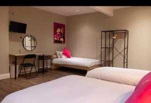 a room with two beds and a desk with a mirror at izzy hotel ltd in Old Walker