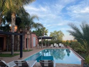 a swimming pool with chairs and an umbrella at Villa Dilyas Marrakech in Tameslouht