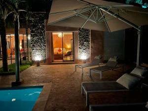 a patio with chairs and an umbrella next to a pool at Villa Dilyas Marrakech in Tameslouht