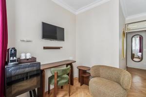 a room with a desk and a tv and chairs at Hotel Du Flaneur in Paris