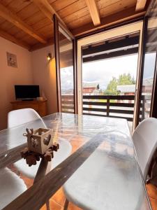 a glass table with white chairs and a large window at Alpine stay at the foot of the slopes in Crest-Voland