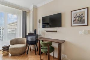 ein Hotelzimmer mit einem Schreibtisch, einem Stuhl und einem Fernseher in der Unterkunft Hotel Le Clery in Paris