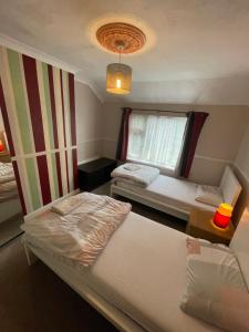 a small room with two beds and a window at Lovely 4 bed house with patio & bbq in Slades Green