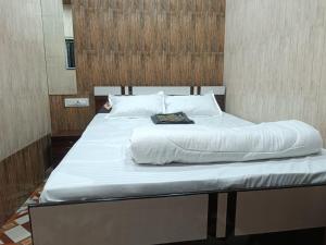 a large white bed with a book on it at Hotel Bhagirath in Mumbai