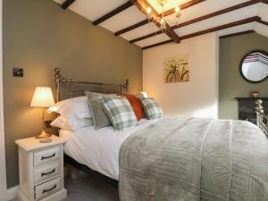 ein Schlafzimmer mit einem Bett und einem Tisch mit einer Lampe in der Unterkunft Chimes Cottage in Guisborough