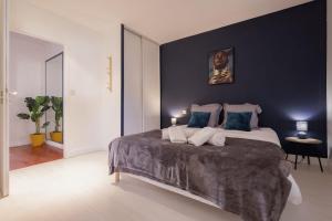 een slaapkamer met een groot bed met blauwe muren bij La Coloc - Chatillon la Palud idéal PROS in Châtillon-la-Palud