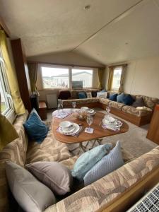 ein Wohnzimmer mit Tisch und Couch in der Unterkunft Lovely 6 Berth Caravan Nearby Hunstanton Beach In Norfolk Ref 23020T in Hunstanton