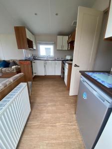 eine kleine Küche mit weißen Schränken und einem Geschirrspüler in der Unterkunft Lovely 6 Berth Caravan Nearby Hunstanton Beach In Norfolk Ref 23020T in Hunstanton