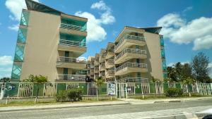 a tall building with a fence next to a street at Beach Place ACONCHEGO e refúgio perto do mar in Cumbuco