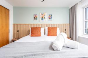 a bedroom with a large white bed with orange pillows at Old Prestwick Point - Donnini Apartments in Prestwick