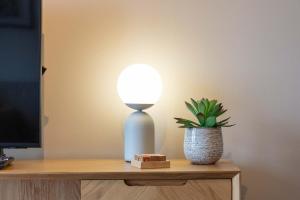 a lamp sitting on a table next to a plant at Old Prestwick Point - Donnini Apartments in Prestwick +13 photos