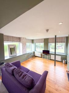a living room with a purple couch and a piano at The Crescent Turner Hotel in Whitstable