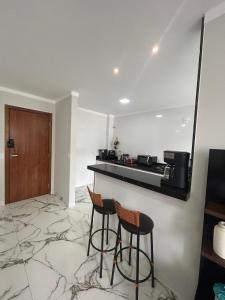a kitchen with two bar stools and a counter at Apartamento grande em Santa Teresa-ES in Santa Teresa