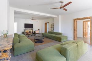 a living room with two green couches and a tv at DOMAINE De PLAISANCE in Cachen