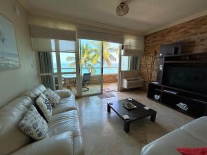 Una sala de estar con un sofá y un televisor. en Beachfront 5th floor at Pelican Reef, en Rincón