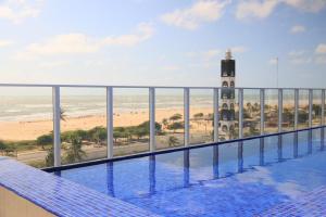 a swimming pool with a view of the beach and a lighthouse at Apartamento Vista Mar atalaia varanda gourmet in Aracaju