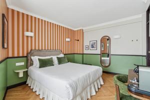 ein Schlafzimmer mit einem Bett mit grünen und orangen Streifen in der Unterkunft Hotel Le Clery in Paris
