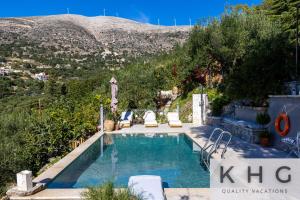 a swimming pool with chairs and a mountain in the background at Anti-Pera Cottage with private pool in Dilinata village! in Argostoli