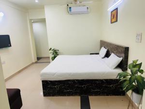 a bedroom with a bed with white sheets and a tv at Hotel jain palace in Chhatarpur +4 photos