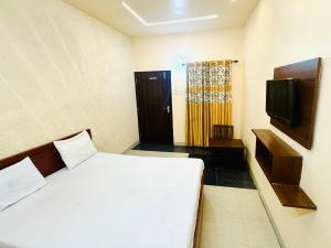 a bedroom with a white bed and a television at Hotel jain palace in Chhatarpur
