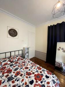 ein Schlafzimmer mit einem Bett mit geblümter Bettdecke in der Unterkunft Elegant 2-bedroom apartment near Paris & Château de Vincennes in Nogent-sur-Marne