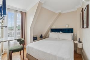Un dormitorio con una cama, una silla y una ventana en Hotel Le Clery, en París