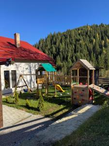a playground in front of a building with trees at Cabana Stânceni in Drăgoiasa