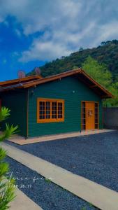 un edificio verde con puertas naranjas y una montaña en Casa no centro de Urubici Dutra Borba, en Urubici