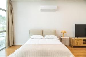 een witte slaapkamer met een bed en een televisie bij Business office - Studio with garage in Linda-a-Velha