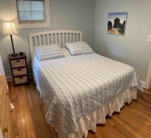 a bedroom with a bed with a striped comforter at Beautiful & Romantic 1BR Cottage w/Beach Locker in Ocean Grove +36 photos