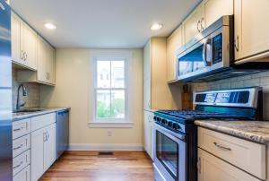 a kitchen with white cabinets and a stove top oven at 3BR Beautiful Remodeled Victorian w/ Beach Locker in Ocean Grove