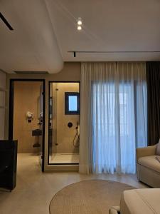 una sala de estar con una puerta de cristal que da a una ducha en Imperial Suites Vlora, en Vlorë