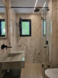 Un baño con lavabo y ducha de cristal. en Imperial Suites Vlora, en Vlorë