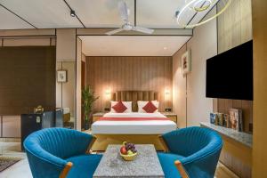 Habitación de hotel con 1 cama y 2 sillas azules en J Residency Near Nizamuddin Railway Station, en Nueva Delhi