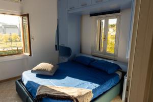 1 Schlafzimmer mit einem Bett mit blauer Bettwäsche und 2 Fenstern in der Unterkunft lakefront and parking - Lakefront Escape in Desenzano del Garda