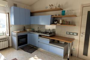 eine Küche mit blauen Schränken und einem Holztisch in der Unterkunft lakefront and parking - Lakefront Escape in Desenzano del Garda