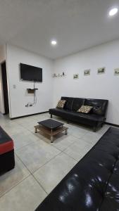 a living room with a black couch and a tv at Large apartment close to everything! North area in Cochabamba