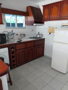 a kitchen with wooden cabinets and a white refrigerator at Chez Rosalie in Lamentin