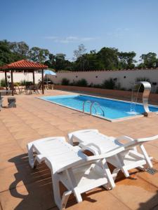 a swimming pool with two white benches next to it at Pousada Pitauá in Socorro