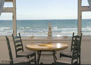 a table and chairs with a view of the ocean at 3 The Moorings, East Wittering in East Wittering