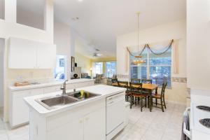 Una cocina blanca con un fregadero y una mesa. en SERENE & ATTRACTIVE 3BR HEATED POOL/SPA HOME, en Estero