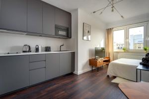 a kitchen with white cabinets and a bed in a room at Studio des roses place des Martyrs hyper centre in Luxembourg