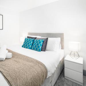 a white bedroom with a large bed with blue pillows at Modern Apartment - Wolverhampton Centre - Fast WiFi - Netflix 12AC in Wolverhampton