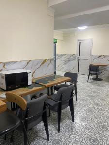 a waiting room with tables and chairs and a microwave at Hostel House ЖК Ожет in Almaty +34 photos