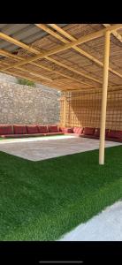 un pabellón con césped verde bajo un techo de madera en Crestora farm, en Ras al Khaimah 3 fotos más