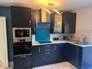 a kitchen with blue cabinets and a sink and a stove at Paradise in Marston Green