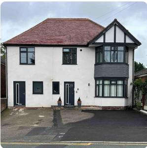 a white house with a black roof at Paradise in Marston Green