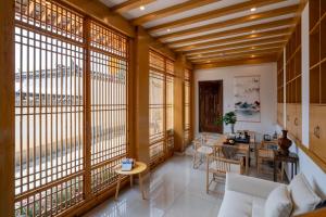 sala de estar con ventanas grandes y mesa en Lijiang Tongfu Inn, en Lijiang