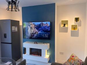 a living room with a fireplace and a tv on a wall at Paradise in Marston Green