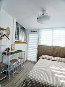 ein Schlafzimmer mit Bett und Schreibtisch und eine Küche in der Unterkunft El rincón zen- Suite independiente con baño privado y kitchenette in Torrevieja